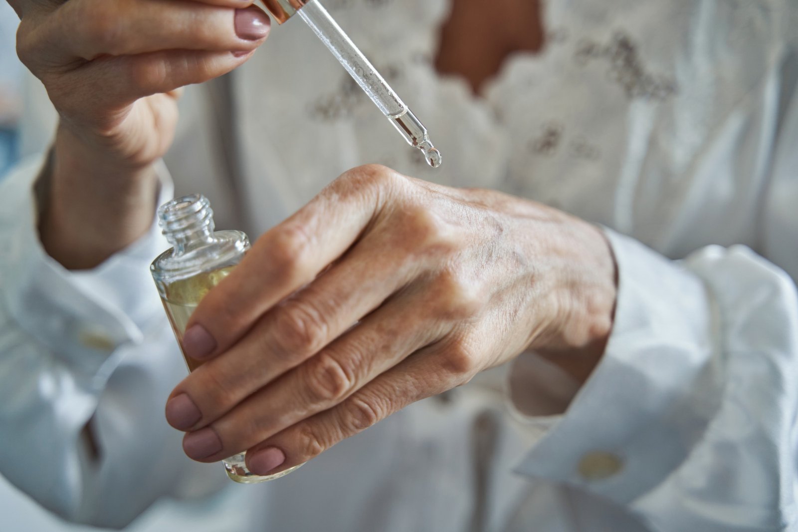 Person applying a drop of skin care liquid from pipette